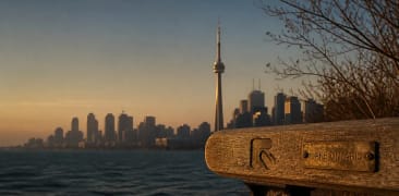 The CN Tower above the Toronto skyline at sunset, seen across Lake Ontario