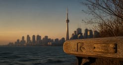 The CN Tower above the Toronto skyline at sunset, seen across Lake Ontario
